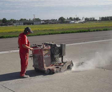 Ein Mitarbeiter Schneidet den Asphalt auf mit einer Maschine