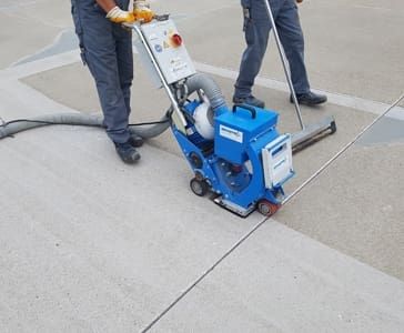 Eine blaue Maschine wir über Betonboden gerollt und säubert ihn dadurch