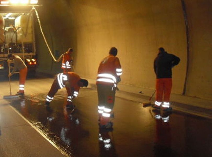 Several employees coating traffic surfaces in a tunnel